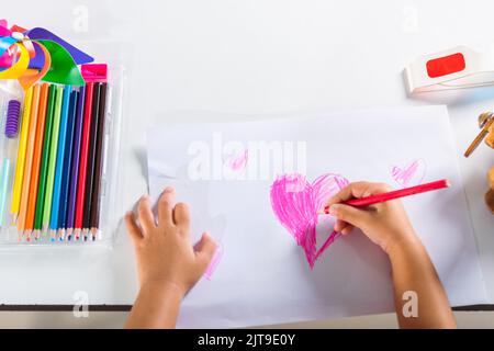 Asiatique mignon enfant préscolaire sourire dessiner les coeurs créatifs amour image à la maison, heureux enfant petite fille coloré dessin coeur rose sur papier blanc, Valent Banque D'Images