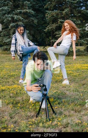 Deux jeunes filles autochtones dansent dans un parc de la ville, tandis qu'un garçon filme avec eux. Les adolescents de la ville et la diffusion en direct. Blogging vidéo Banque D'Images