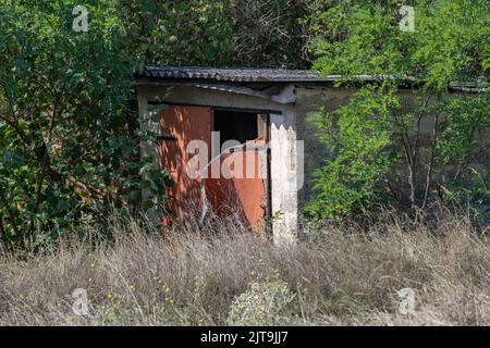 Un hangar abandonné et abandonné avec une porte ouverte cassée Banque D'Images