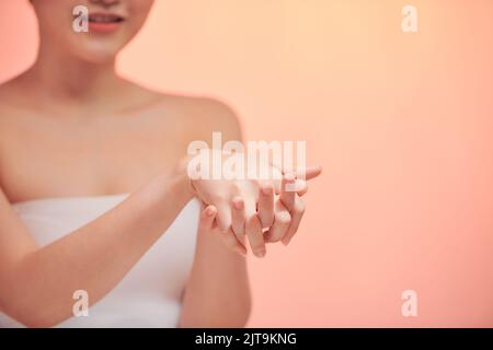 La fille se sent les mains avec une crème cosmétique de départ pour un jeune et l'élasticité d'une peau Banque D'Images