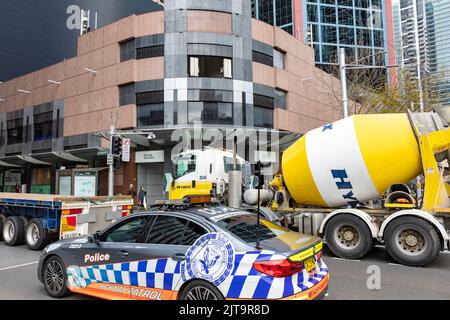 Voiture de police de Sydney et camion de béton prêt à mélanger sur la rue Bathurst dans le centre-ville de Sydney, Nouvelle-Galles du Sud, Australie Banque D'Images