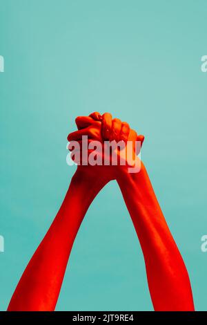 Amitié. Mains authentiques gesturant isolées sur fond de couleur cyan à la lumière rouge de néon. Concept de relation, de communauté, de soins, de soutien Banque D'Images