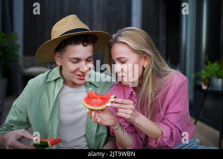 Joyeux jeune couple amoureux mangeant une tranche de pastèque ensemble Banque D'Images