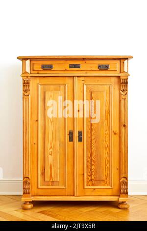 Armoire ou placard en bois d'époque restaurée contre le mur blanc d'un ancien bâtiment avec parquet et stuc plâtrage, espace de copie. Banque D'Images