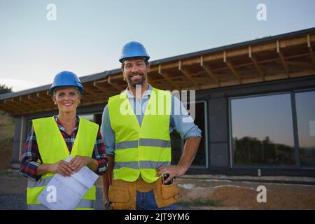 Des ingénieurs de construction ou des architectes avec des plans-plans visitant le site de construction écologique de la maison de cadre en bois Banque D'Images