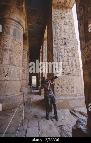 White Man Tourist près des piliers peints de l'Égypte antique du complexe du Temple de Dendera dans le sud-est de Dendera, Egypte Banque D'Images