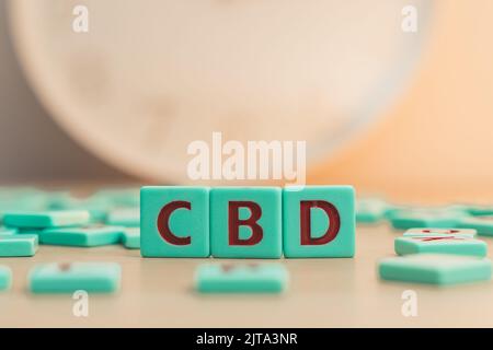 Le mot CBD fait de petites pièces de jeu colorées avec des lettres imprimées sur elles. Le cannabis comme médecine alternative à base de plantes et la thérapie chimique. Photo de haute qualité Banque D'Images