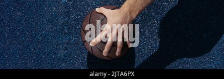 vue partielle d'un joueur de basket-ball prenant le ballon de l'asphalte, bannière Banque D'Images