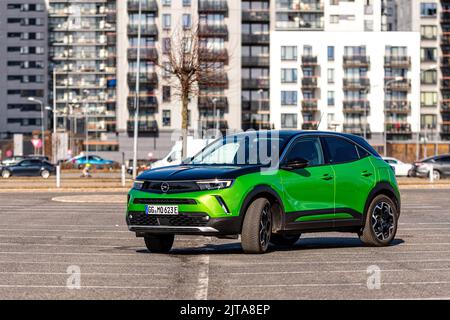 Riga, Lettonie - 26 mars 2021: Véhicule électrique vert Opel Mokka-e dans le parking sur le fond d'une zone résidentielle urbaine Banque D'Images