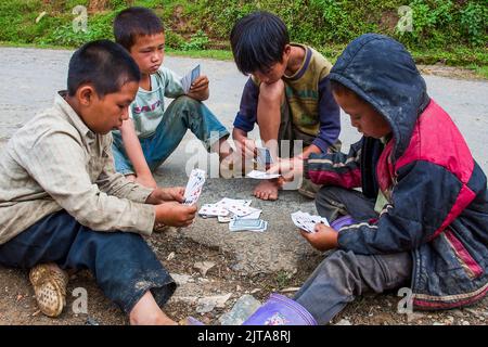 Vietnam, les garçons de la tribu Hmong Noire jouent des cartes sur les outsjupes de Sapa. Sapa est une ville près de la frontière chinoise et populaire par les touristes en raison de la scen Banque D'Images