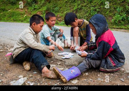 Vietnam, les garçons de la tribu Hmong Noire jouent des cartes sur les outsjupes de Sapa. Sapa est une ville près de la frontière chinoise et populaire par les touristes en raison de la scen Banque D'Images