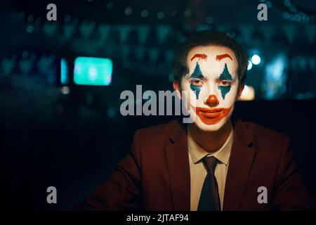 Guy en costume et cravate avec le maquillage Joker regarde la caméra. Banque D'Images