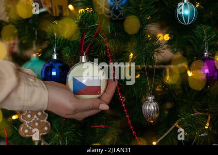 Une fille porte une décoration sur un arbre de Noël avec le drapeau de la République tchèque Banque D'Images