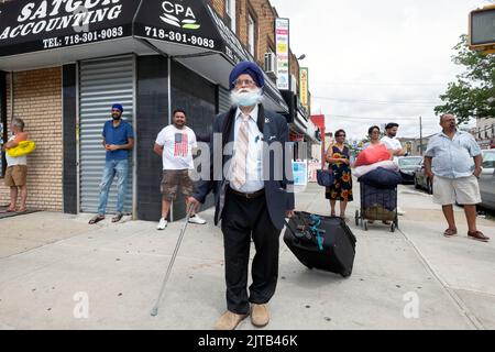 Une scène de rue sur 101st Avenue avec un voyageur sikh au premier plan et d'autres hommes et femmes marchant et traîner. À Queens, New York. Banque D'Images