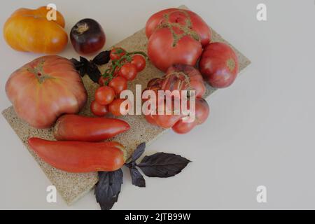 tomates mûres fraîches de formes et de variétés variées sur fond blanc. Banque D'Images