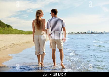 couple heureux marchant dans l'eau le long de la plage d'été Banque D'Images