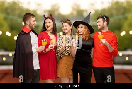 des amis heureux en costumes d'halloween sur gris Banque D'Images