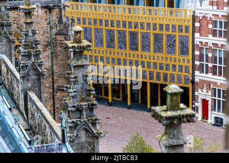 Le Stadhuiskwartier à Deventer, l’une des neuf villes hanséatiques historiques sur la rivière IJssel, dans la province d’Overijssel, aux Pays-Bas, est l’extension de l’hôtel de ville achevée en 2016 par les architectes Neutelings Riedijk. Sa façade en verre encadrée de jaune porte l’œuvre „Deventer Raamwerk“ (Cadre de Deventer) de l’artiste Loes ten Anscher : 2 264 empreintes digitales d’habitants de Deventer moulées en aluminium. Vu depuis la tour de l’église Saint-Lebuïnus, le bâtiment s’élève entre des maisons à pignons historiques. Banque D'Images