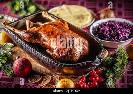 Rôti d'oie de Noël au chou rouge, pain plat dans un plat original sur la table de fête. Banque D'Images