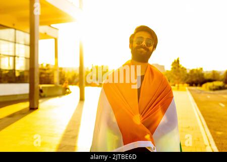 homme indien portant fièrement le drapeau des portes d'entrée dans le parc de coucher de soleil d'été Banque D'Images