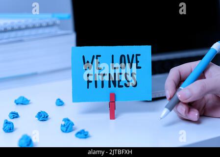 Panneau montrant We Love Fitness. Photo conceptuelle avoir l'affection pour les exercices de sport bonne alimentation saine Dame en costume tenant le stylo symbolisant Banque D'Images