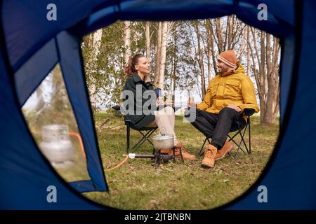 couple de boire de la bière et de la nourriture de cuisine au camp de tente Banque D'Images