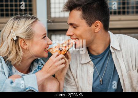 couple heureux de manger de la pizza à l'extérieur Banque D'Images