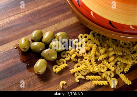 Olives vertes, pâtes et Tajine rouge sur comptoir en bois horizontal Banque D'Images