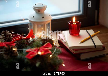 couronne de noël, livres, bougie, lanterne sur la fenêtre Banque D'Images