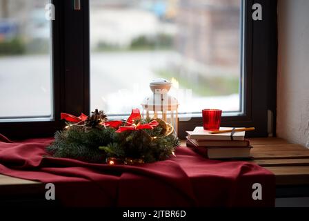 couronne de noël, livres, bougie, lanterne sur la fenêtre Banque D'Images