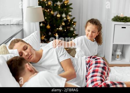 une fille heureuse réveille ses parents le matin de noël Banque D'Images