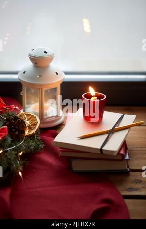 couronne de noël, livres, bougie, lanterne sur la fenêtre Banque D'Images