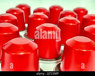 Un gros plan de capsules de café rouges sur une surface blanche Banque D'Images