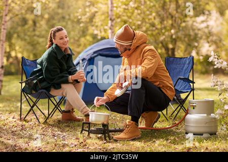 couple de boire de la bière et de la nourriture de cuisine au camp de tente Banque D'Images