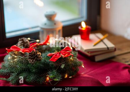 couronne de noël, livres, bougie, lanterne sur la fenêtre Banque D'Images