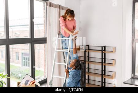 femmes qui pendent le rideau à la maison et font cinq hauts Banque D'Images