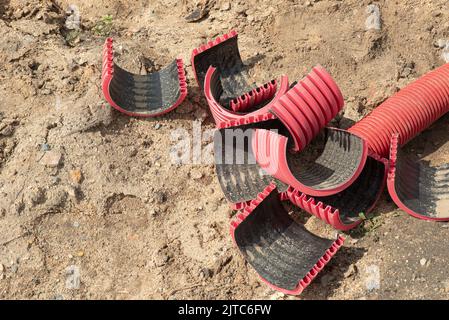 Morceaux coupés de tuyau flexible de drainage terrestre à bobine rouge. Travaux sur le chantier. Banque D'Images