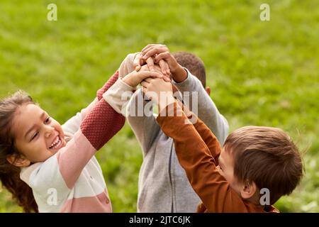 des enfants heureux jouant et se empilant les mains au parc Banque D'Images