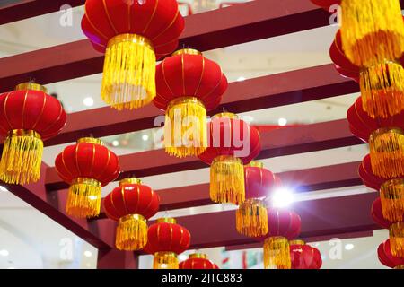 Photo d'une série de lanternes rouges chinoises avec des bandes jaunes, accrochées à des morceaux de bois rouges pour la décoration du nouvel an Banque D'Images