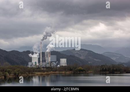 Cheminée et fumée épaisse provenant d'une tour de centrale thermique, une colline couverte de forêt en arrière-plan Banque D'Images