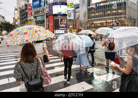 Des piétons avec des parasols traversent l'intersection multidirectionnelle de traversée de brouille connue sous le nom de Shibuya Crossing dans Shibuya Ward, Tokyo, Japon. L'intersection est considérée comme l'intersection piétonne la plus achalandée au monde. Banque D'Images