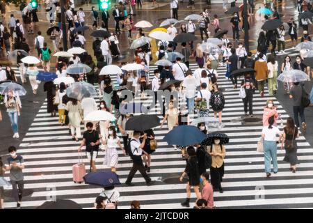 Des piétons avec des parasols traversent l'intersection multidirectionnelle de traversée de brouille connue sous le nom de Shibuya Crossing dans Shibuya Ward, Tokyo, Japon. L'intersection est considérée comme l'intersection piétonne la plus achalandée au monde. Banque D'Images