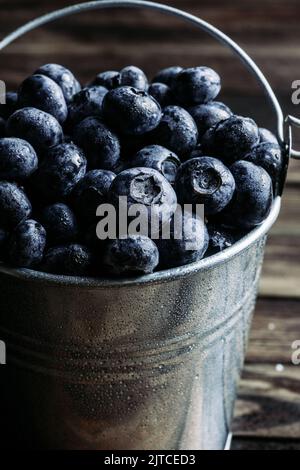 Bleuets en seau en métal sur fond sombre Banque D'Images