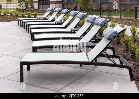 Chaises longues vides dans l'arrière-cour du complexe résidentiel, espace de loisirs, beaucoup de chaises longues avec bâtiment sur fond Banque D'Images