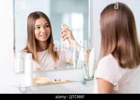 adolescente utilisant un spray coiffant dans la salle de bains Banque D'Images