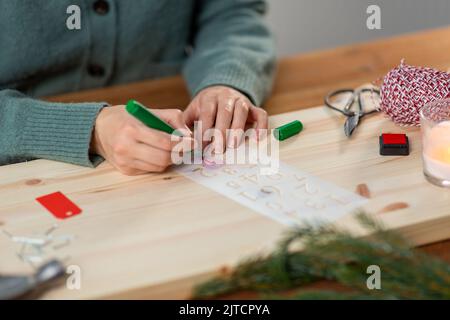 les mains avec le pochoir et le dessin de marqueur sur noël Banque D'Images