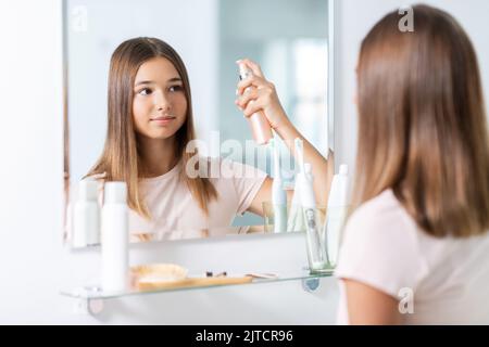 adolescente utilisant un spray coiffant dans la salle de bains Banque D'Images