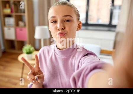 fille prenant le selfie à la maison et montrant la paix Banque D'Images