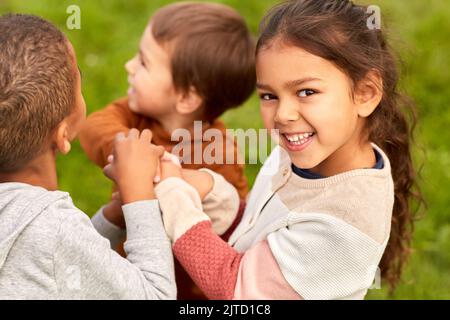 des enfants heureux jouant et se empilant les mains au parc Banque D'Images