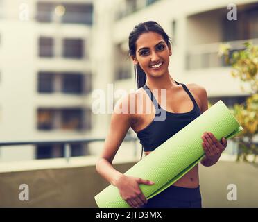 Le yoga vous fait gagner du temps et de l'argent. Une belle jeune femme pratiquant le yoga en plein air. Banque D'Images